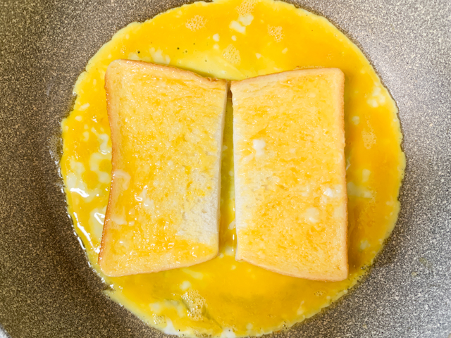 フライパンに卵液を流し込んだら、食パンの片面に卵液をつけて裏返します