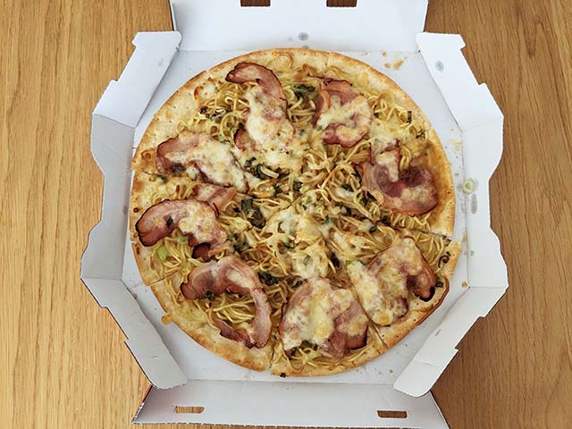 天下一品とピザハットのコラボ商品「こってり風ラーメンピザ」がテーブルに置かれフタが開けられている様子
