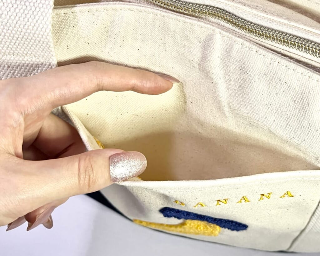 「東京ばな奈の日 トートバッグ」の外ポケットを手で開いている画像