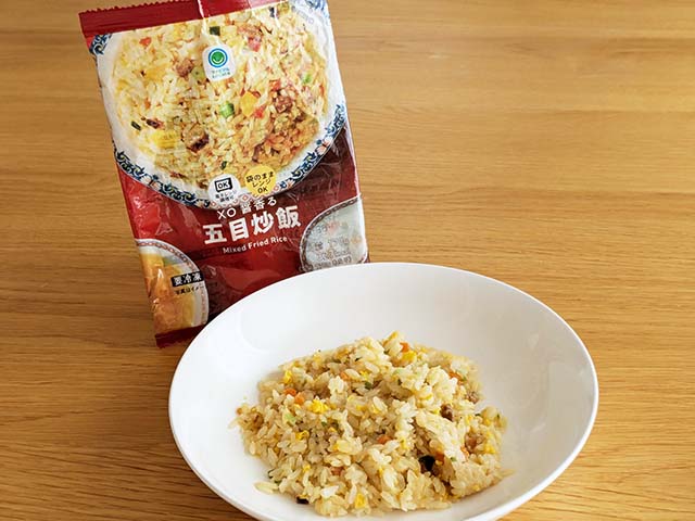 皿に盛られ加熱した【ファミリーマート】「香味油で仕上げた五目炒飯」と外袋がテーブルに並んでいる様子