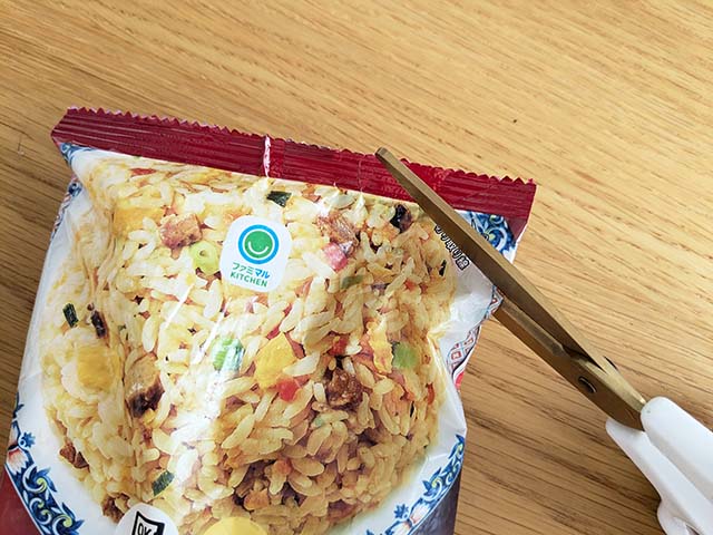 【ファミリーマート】「香味油で仕上げた五目炒飯」の外袋をハサミでカットしている様子