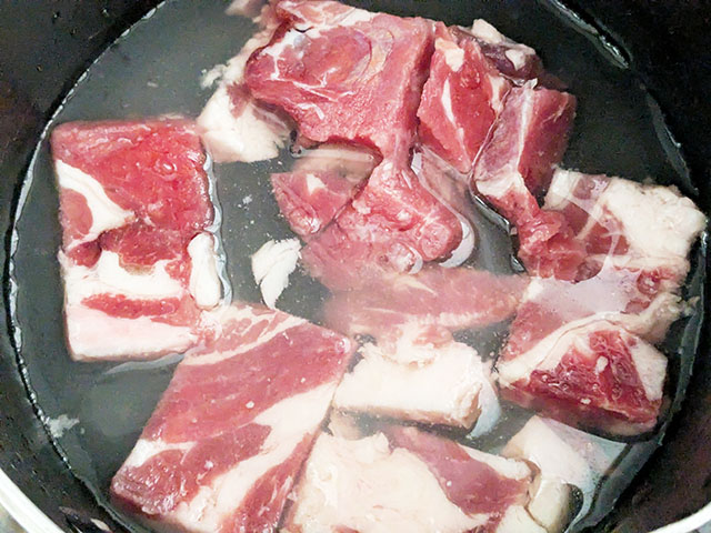 業務スーパー「牛赤身スジ肉」を鍋に入れ下処理している様子