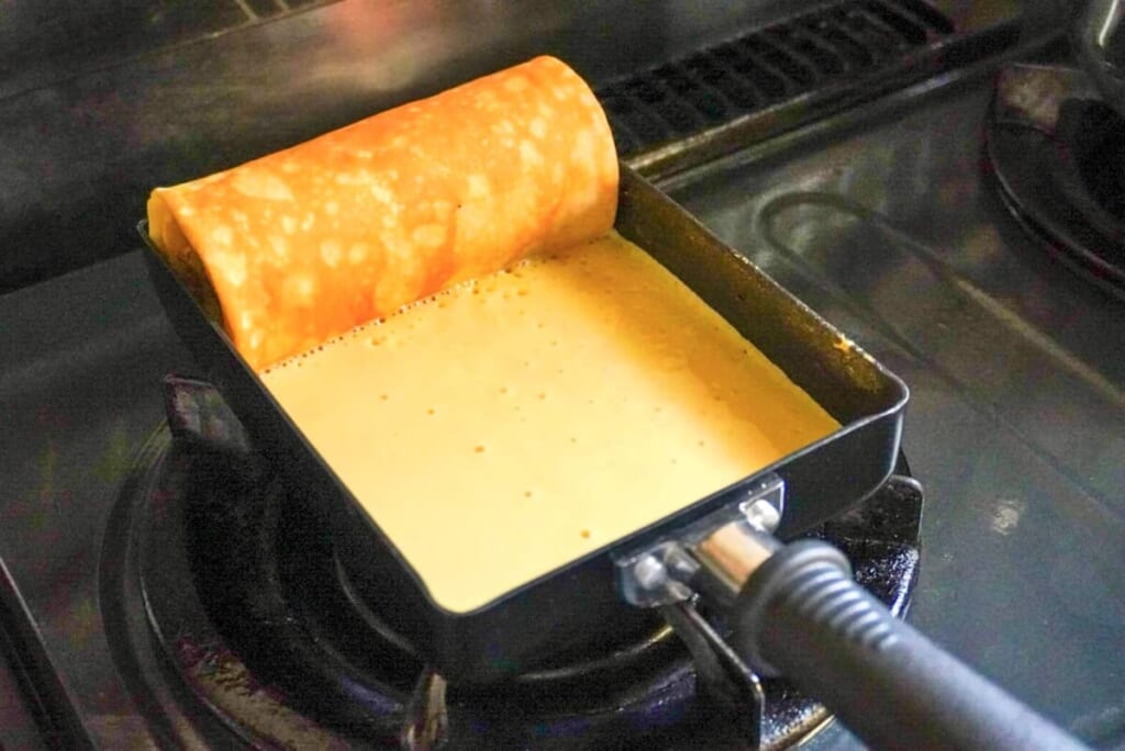 卵焼き器に生地を入れ、バナナと一緒に焼いているようす