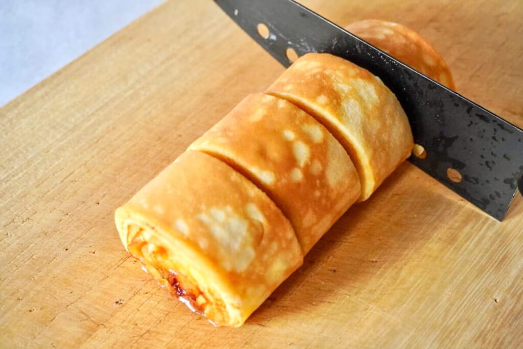 まな板の上で粗熱をとった「バナナバームクーヘン」を包丁でカットしているようす