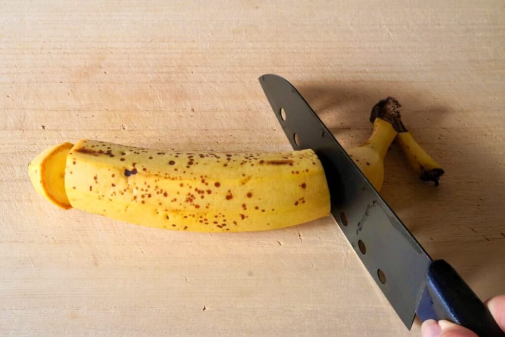 バナナをまた板に乗せ包丁でカットしているようす