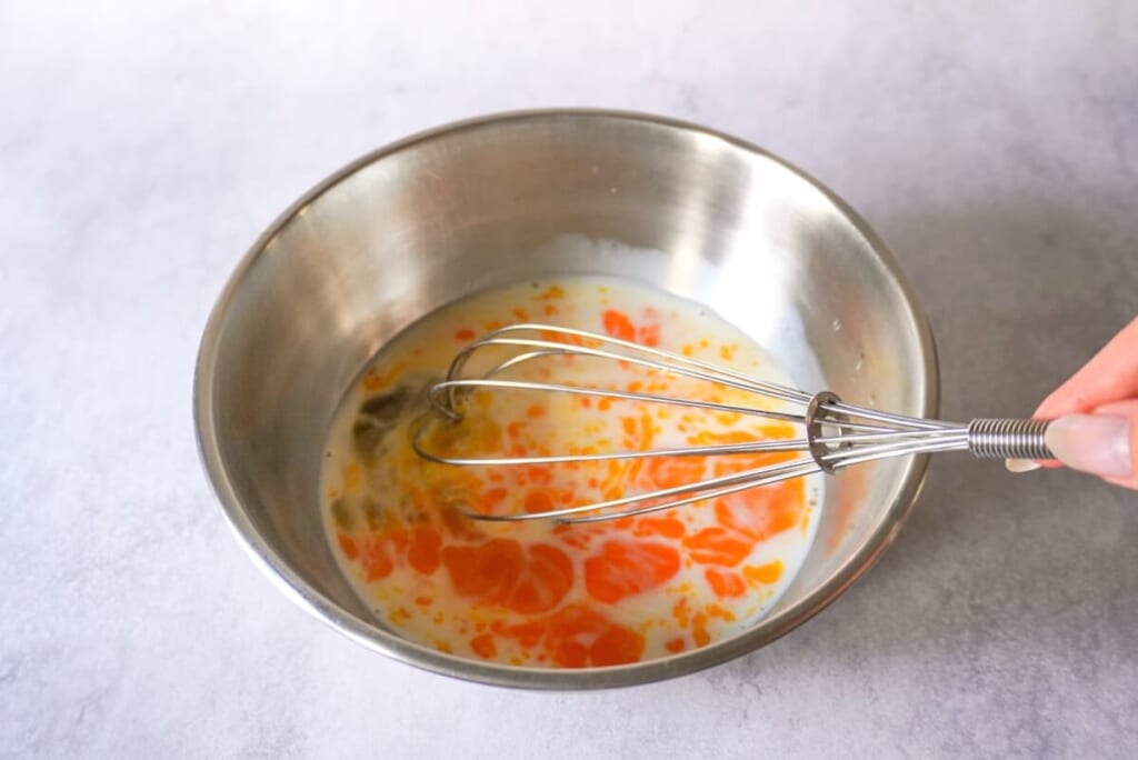 ボウルに入れた卵、牛乳、はちみつを泡だて器で混ぜているようす