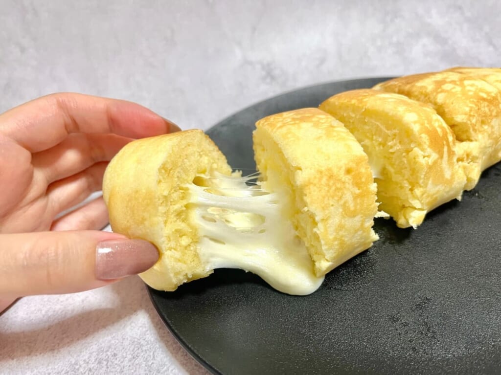 さけるチーズとホットケーキミックスが材料の、卵焼き器で作る「チーズドッグ」。切り分けて手で持ち、チーズを伸ばした様子