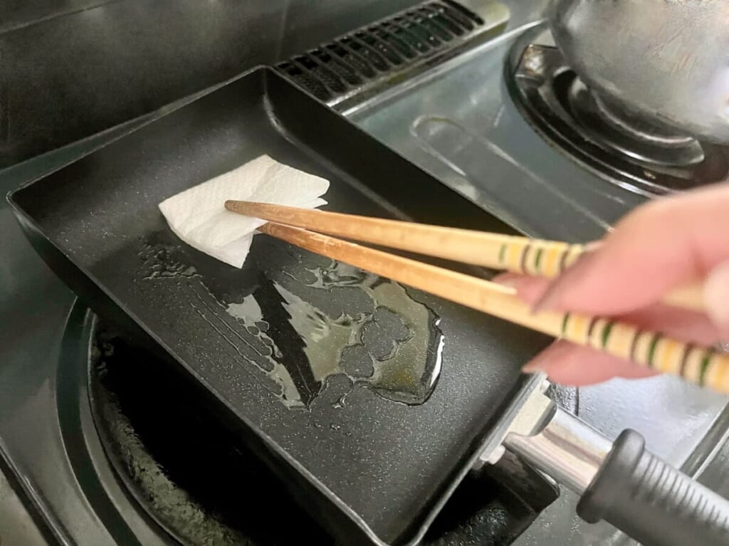 卵焼き器にサラダ油を引き、キッチンペーパーで薄く伸ばしている様子