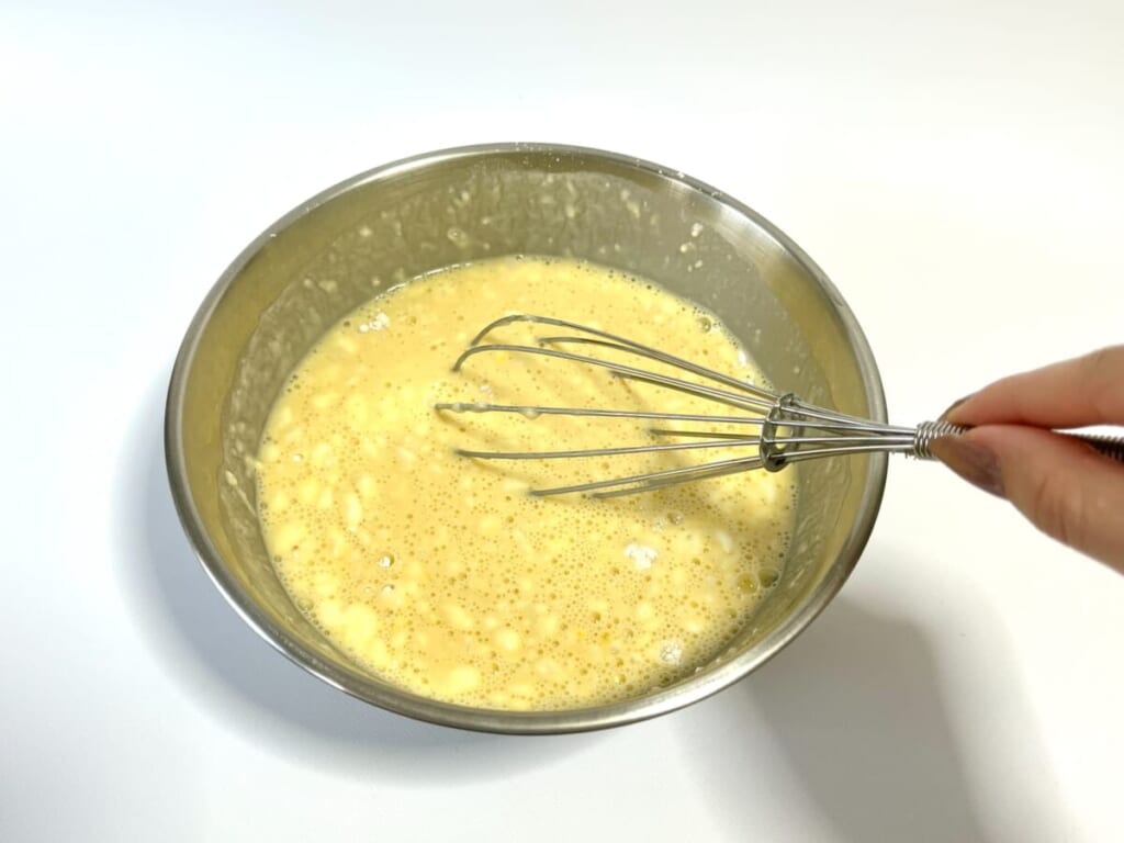 ボウルにたこ焼粉、卵、水を入れ泡だて器で混ぜている様子