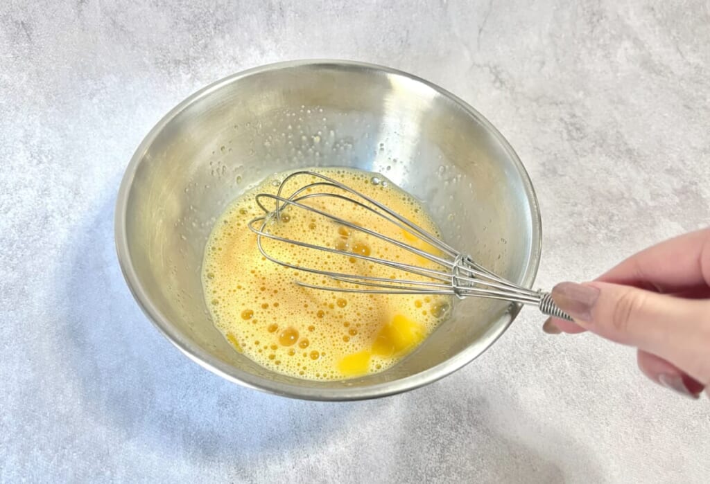 ボウルに卵とグラニュー糖を入れ泡だて器で混ぜている様子