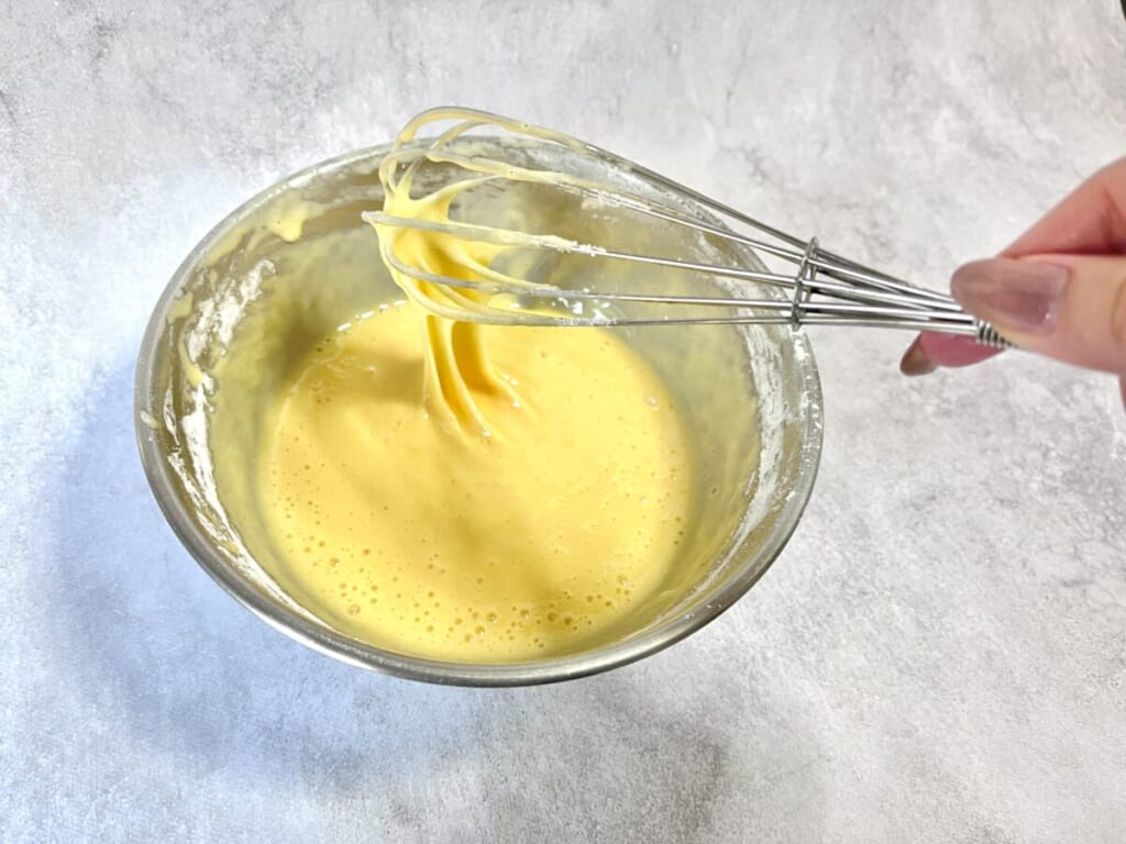ボウルに卵とグラニュー糖、ホットケーキミックスを入れ、泡だて器で混ぜている様子