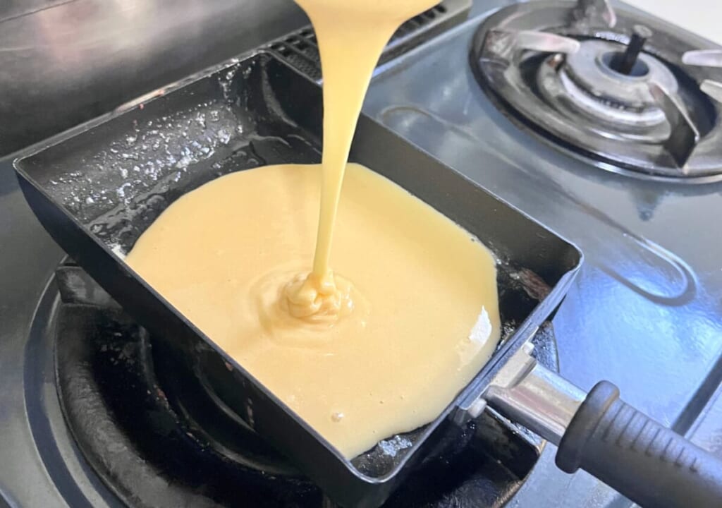 「いちごのキャンドルケーキ」の生地を卵焼き器に流し入れている様子