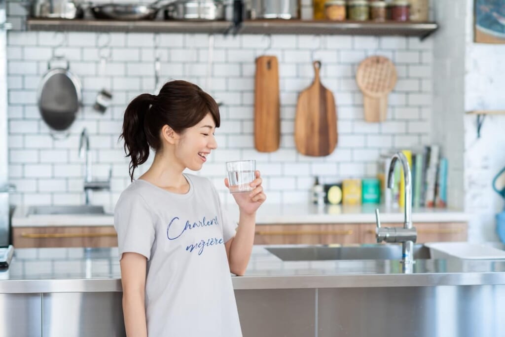 キッチンで水を飲む女性